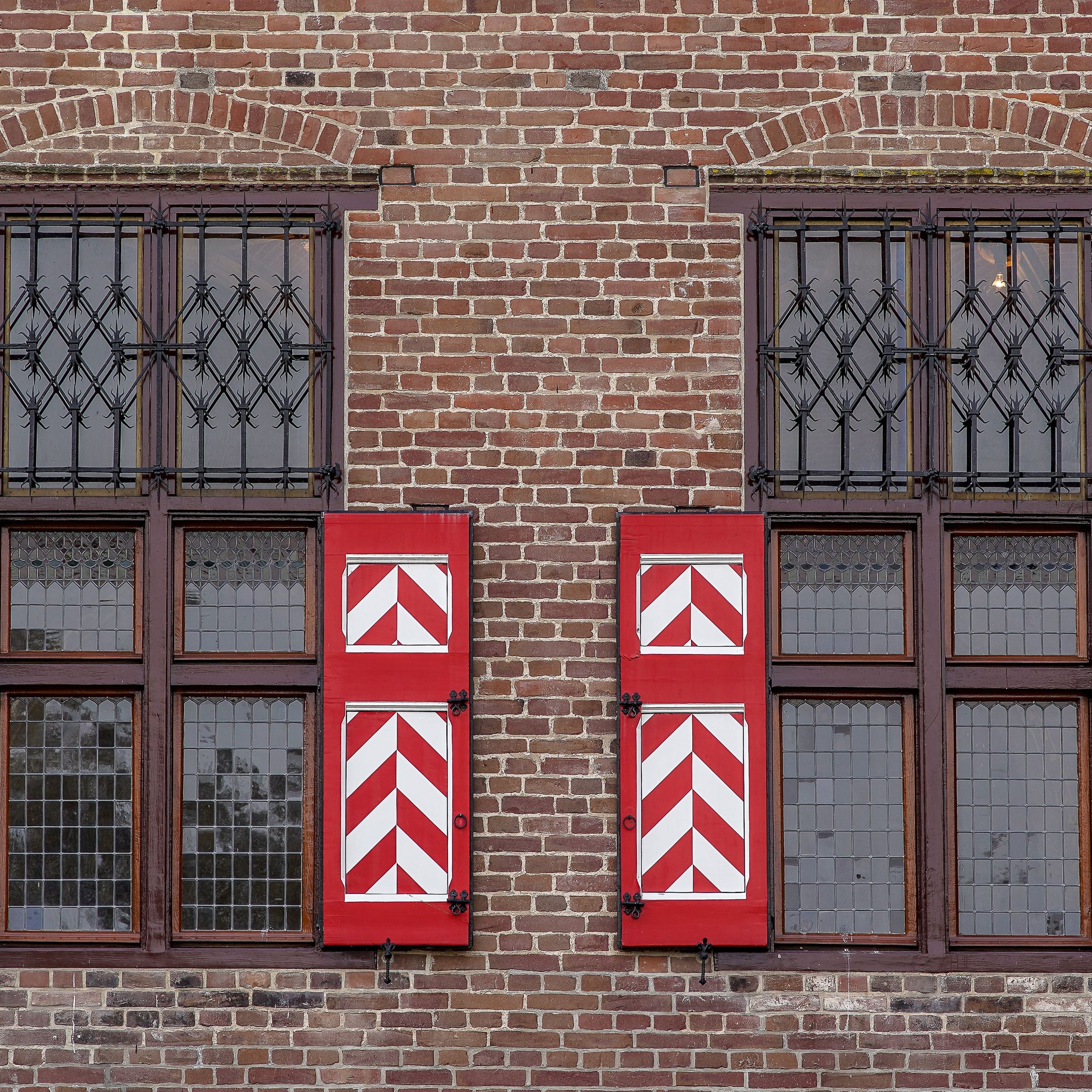 Façade de maison de ville en brique et enduit, volets bois et balcons en fonte